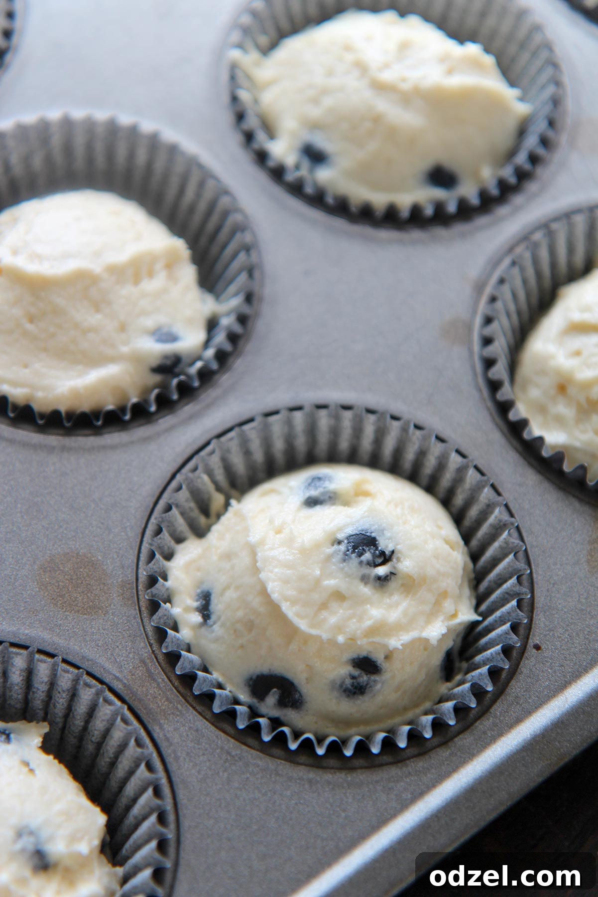 Blueberry Cloud Cupcakes 3 Cupcake batter being carefully spooned into individual muffin tin liners, ready for the oven