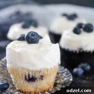 A perfectly baked blueberry cupcake with a swirl of cream cheese frosting