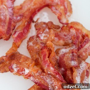 One pound of golden-brown, crispy bacon laid out on a white chopping board, ready to be served.