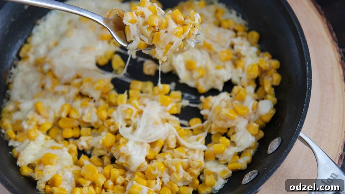 a fork, cheese, and corn in a black skillet.
