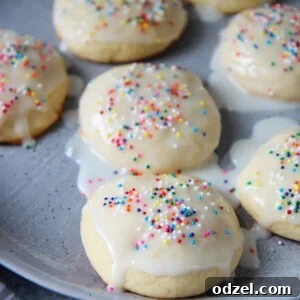 Seven Italian lemon ricotta cookies with a glaze and sprinkles on a gray plate.