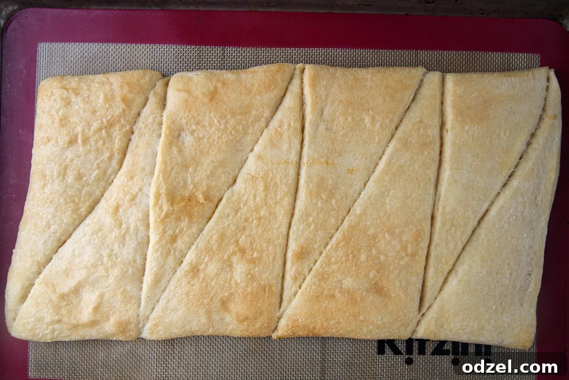 Eight perfectly baked crescent rolls laid out and pressed together on a baking sheet, forming a rectangular, golden-brown crust, ready for cooling.