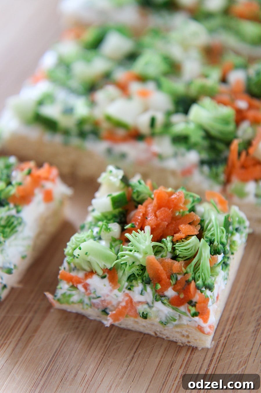 Two perfectly squared vegetable bars artfully arranged on a light wooden board, showcasing their vibrant colors and appealing layers.