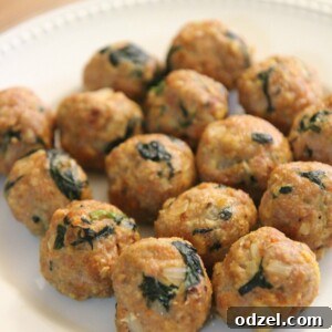 Fifteen beautifully baked spinach and turkey meatballs arranged on a white plate, ready to be served or added to your favorite dish.
