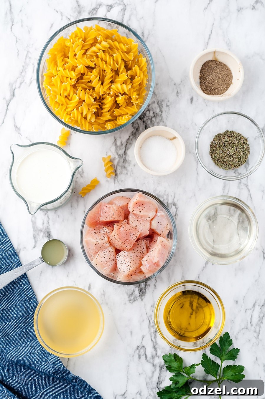 A rustic display of key ingredients for chicken thyme pasta: chicken, fusilli pasta, cream, fresh thyme, garlic, and a bottle of white wine.