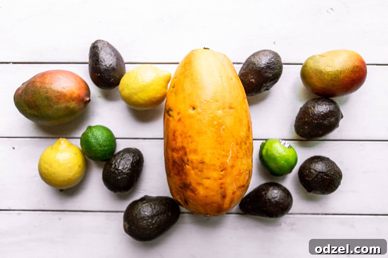 Layered Ethiopian Spris 3 A vibrant selection of fresh, ripe tropical fruits including papayas, mangoes, avocados, lemons, and limes artfully arranged on a clean white surface, ready for blending into an Ethiopian Spris.