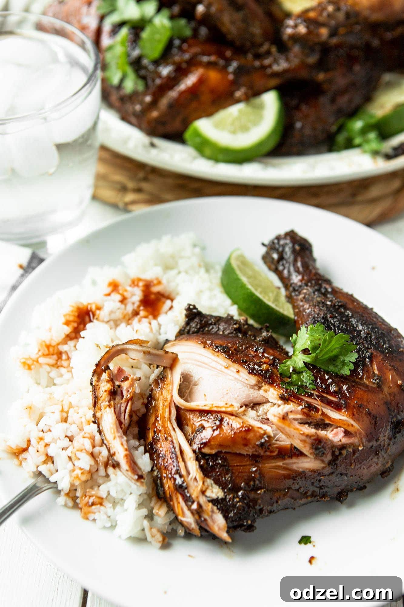 Caribbean Heat Chicken 4 A perfectly cooked Jamaican jerk chicken leg quarter served with fresh lime, cilantro, a scoop of white rice, and a drizzle of pineapple sauce on top of the rice.
