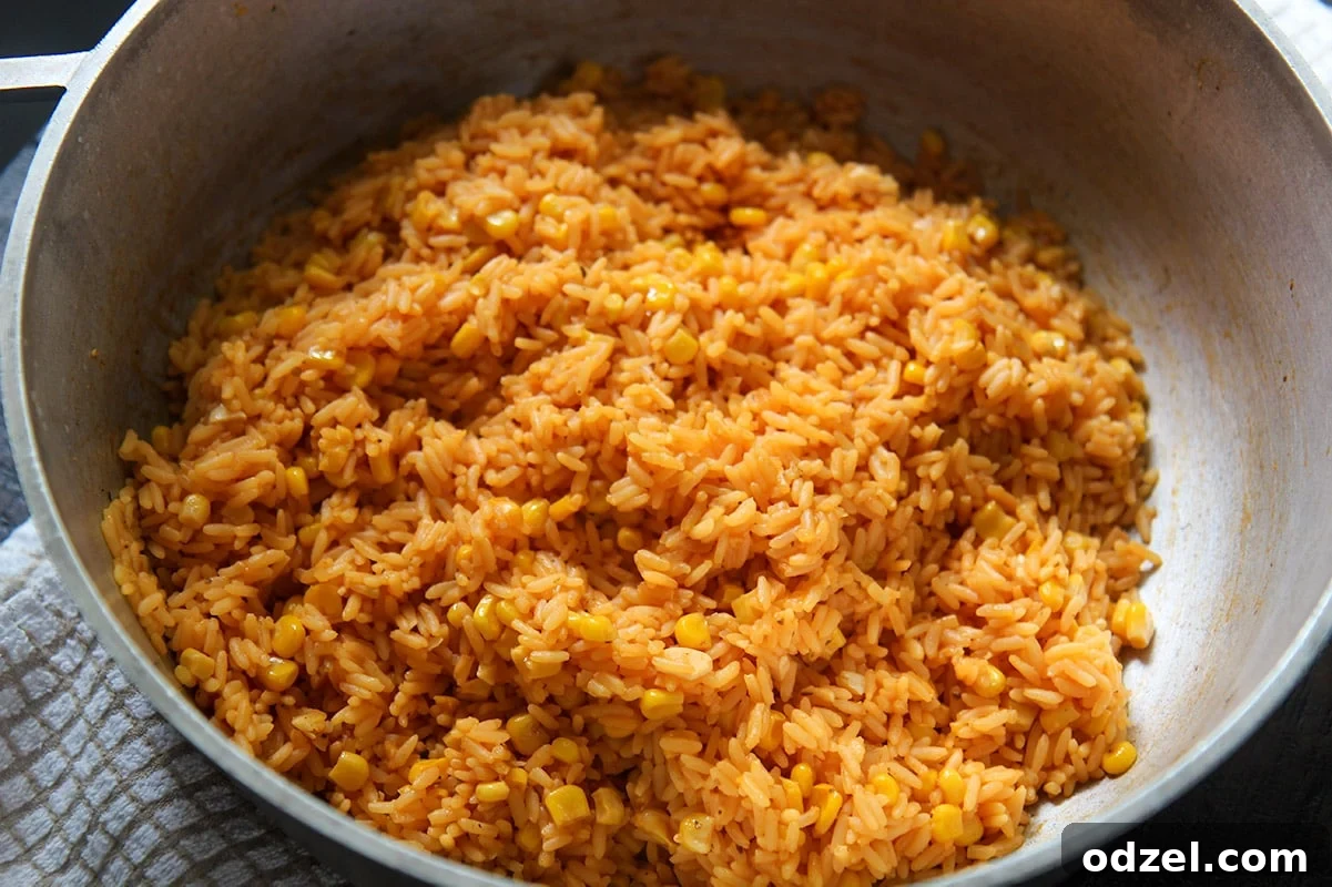 Golden Rice and Sweet Corn Pilaf 3 A close-up, horizontal shot of perfectly cooked Cuban yellow rice speckled with bright corn kernels, resting warmly in a pot.