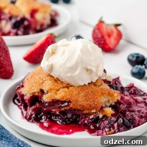berry cobbler on a white plate with vanilla ice cream on top. berries and a baking dish in the background.