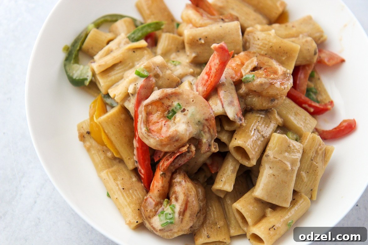 Creamy Instant Pot Rasta Pasta 3 Close-up of creamy Rasta Pasta with shrimp and colorful peppers in a white bowl, garnished with fresh scallions.