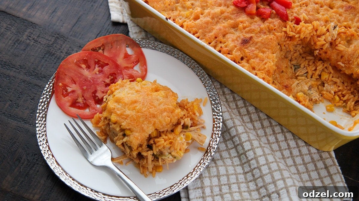 Royal Cuban Rice Bake 5 a serving of yellow rice, shredded chicken, cheese, and two tomato slices on a white plate with a fork.