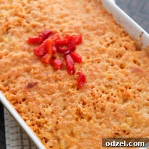 arroz imperial in a yellow casserole dish with melted yellow cheese and red peppers on the center.