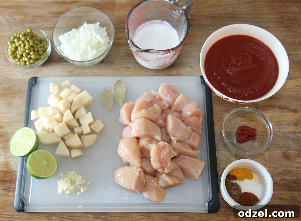 Velvet Coconut Chicken Curry 3 Various fresh ingredients for coconut chicken curry laid out on a wooden cutting board with small bowls of spices.