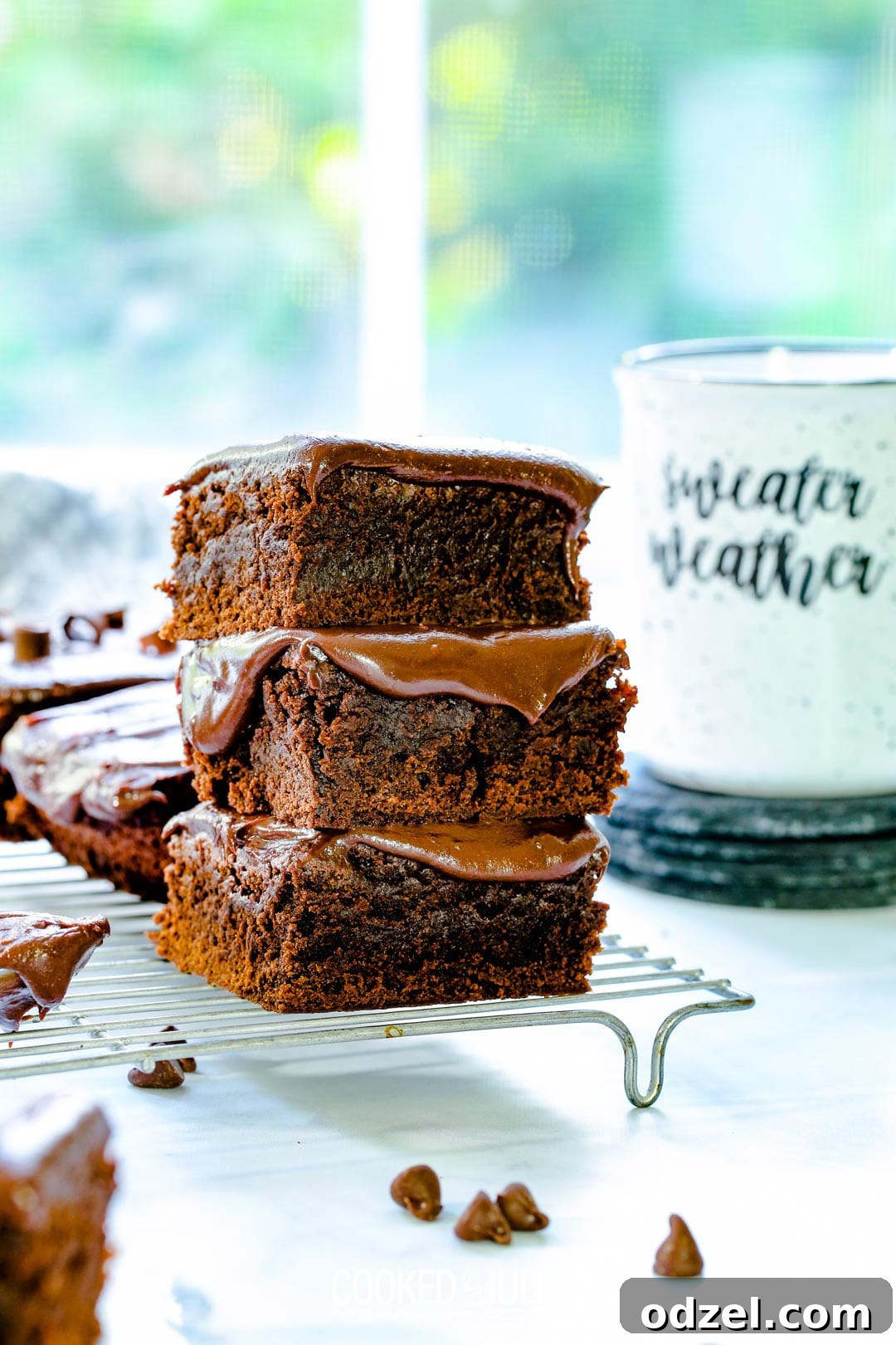 A beautifully stacked trio of decadent chocolate fudge brownies, highlighting their thick layer of glossy, rich fudge and dense texture.