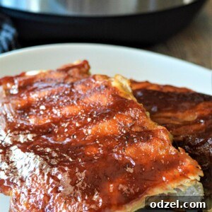 Two racks of bbq ribs on a white plate up close.