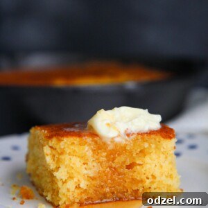 a slice of cornbread with butter and honey on a plate.