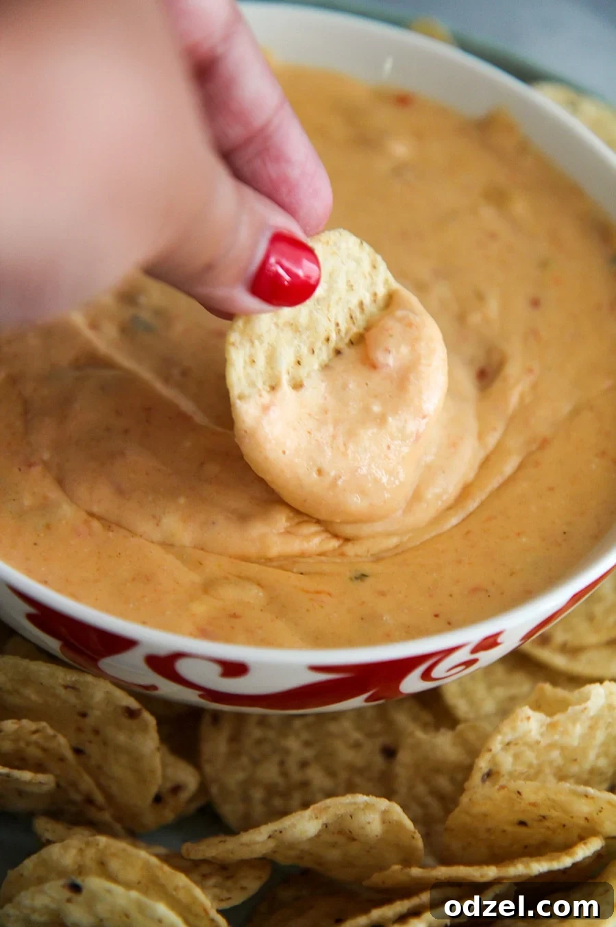 Creamy Instant Pot Queso Dip 4 A crispy tortilla chip being expertly dipped into a bowl of rich, yellow Instant Pot Queso, showcasing its thick and creamy texture.