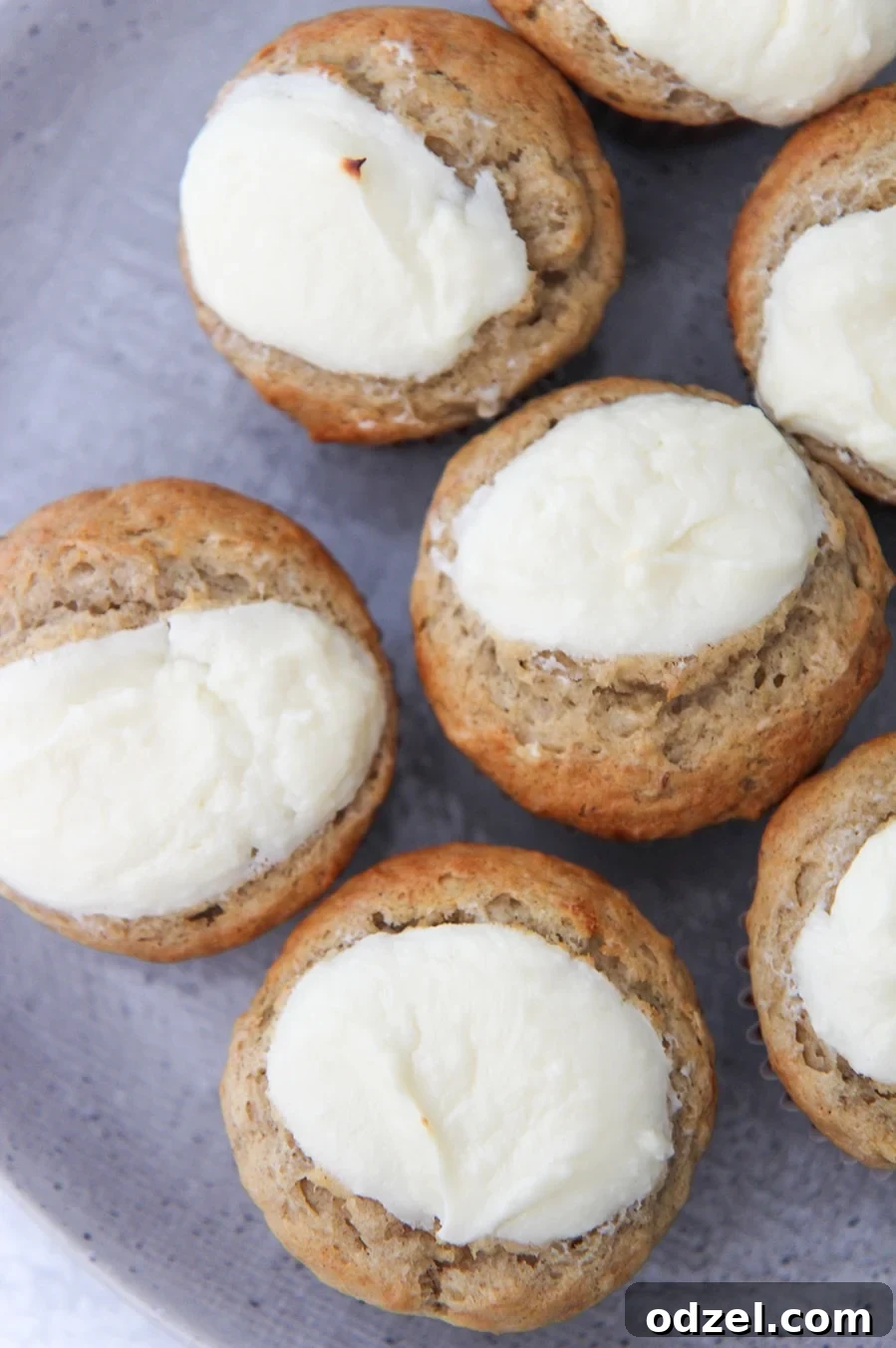 Close-up of a moist cream cheese banana muffin on a gray plate, showcasing the creamy filling