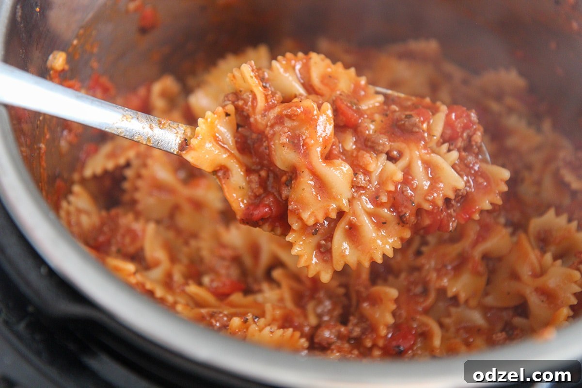 Instant Pot Lasagna Shortcut 3 Close-up of a spoonful of Instant Pot Lazy Lasagna, showing farfalle pasta coated in sauce with melted cheese.