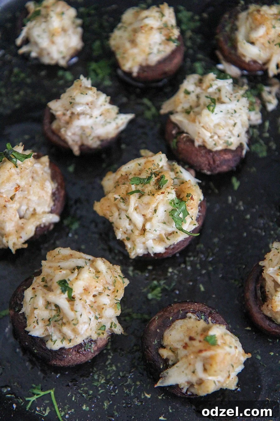 Perfectly baked crab stuffed mushrooms arranged beautifully in a rustic cast iron skillet.