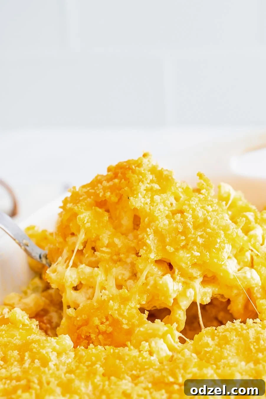 A close-up shot of a spoonful of baked mac and cheese, showcasing its gooey texture and golden-brown topping.
