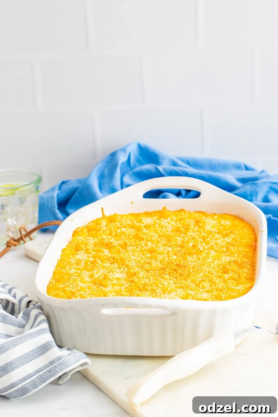 A large white casserole dish filled with golden-yellow baked mac and cheese, garnished slightly.