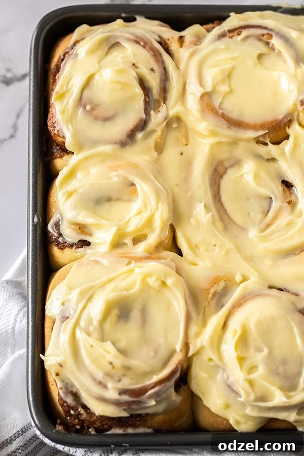 Six jumbo cinnamon rolls with thick cream cheese frosting up close.