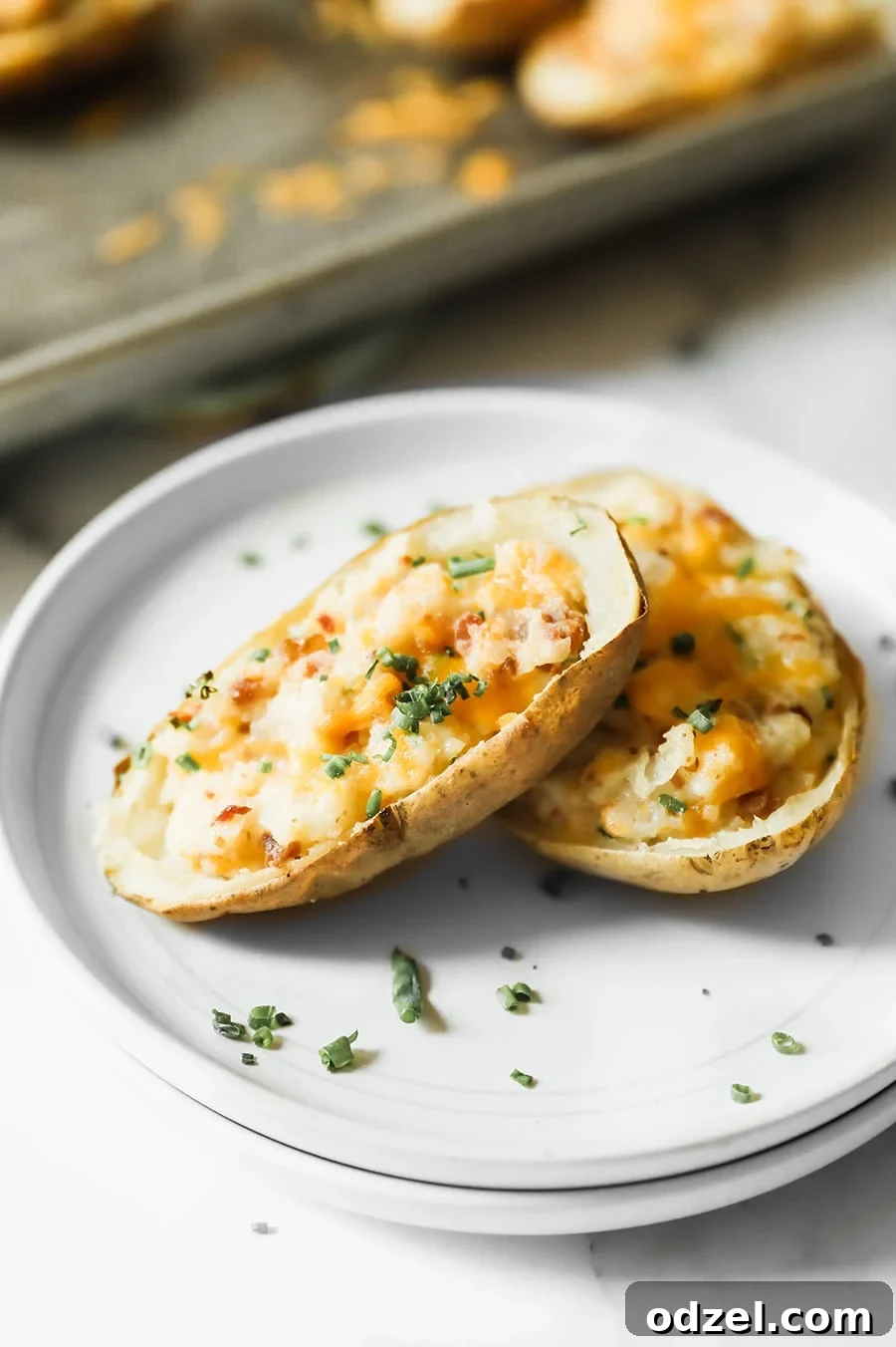 Ultimate Stuffed Potatoes 4 Two perfectly golden-brown twice baked potatoes, garnished with fresh green herbs, resting on a white oval plate, ready to be served.