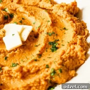 mashed sweet potatoes with butter and green herbs on top.