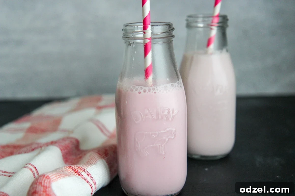 Sweet Berry Milk Infusion 3 Two aesthetically pleasing milk jugs filled with delightful strawberry milk, accompanied by elegant straws and a rustic red and white towel on the side, creating a warm, inviting scene.