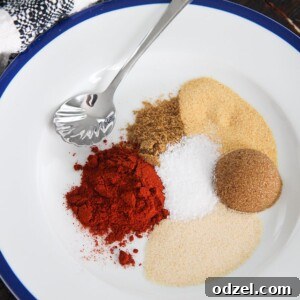 brown sugar and 5 spices on a white plate with a small spoon and towel on the side.