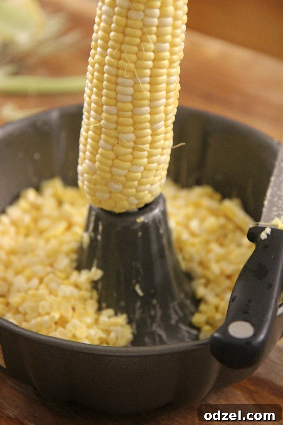 Several corn on the cob pieces arranged artistically inside a bundt pan, with a kitchen knife resting beside them, highlighting the fresh ingredients.