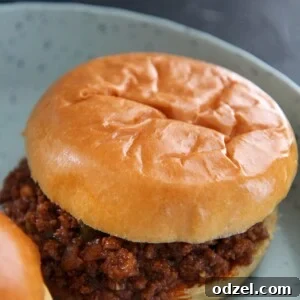 A sloppy joe up close on a blue plate, highlighting the delicious texture and sauce.