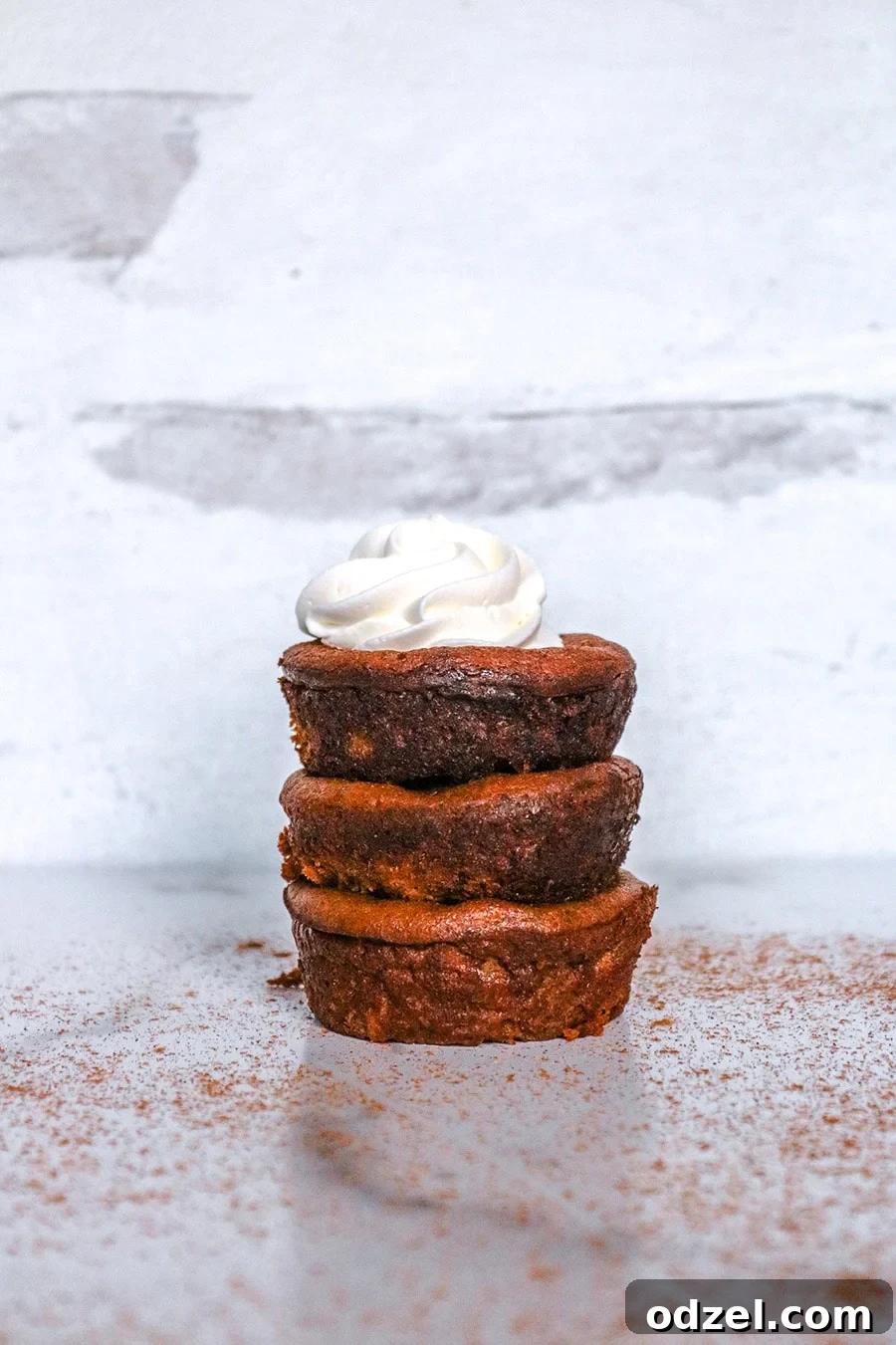 Delectable Keto Mini Pumpkin Tarts 3 A trio of beautifully arranged keto mini pumpkin pies, generously topped with whipped cream, demonstrating their perfect individual serving size and festive appeal.