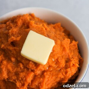 A small white bowl filled with mashed sweet potatoes and a slice of butter on top.