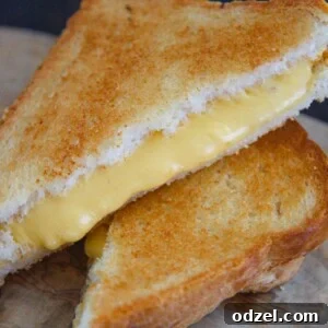 two grilled cheese sandwiches stacked on top of each other on a wooden board.