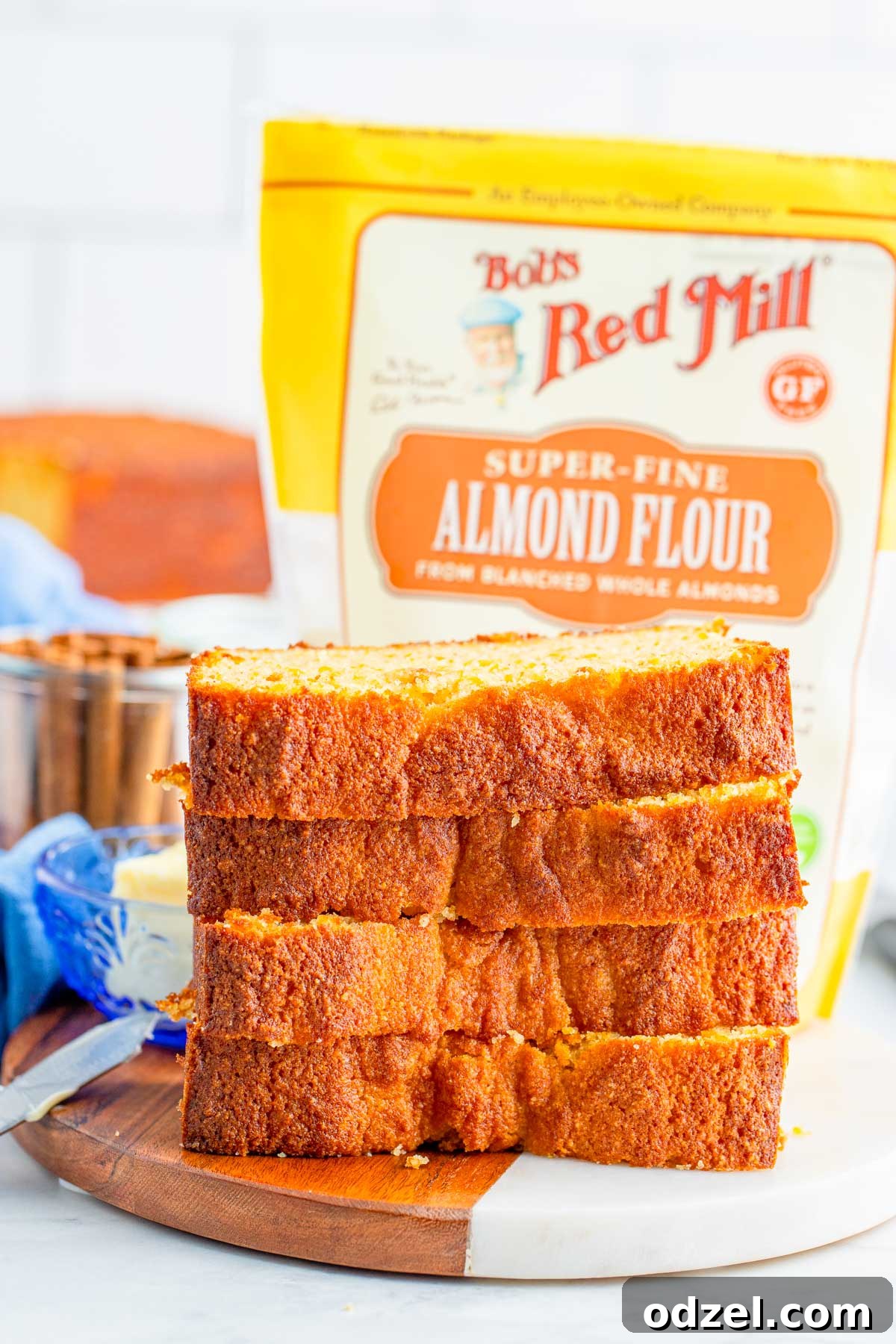 Four slices of gluten-free sweet potato bread beautifully arranged, with a package of Bob's Red Mill flour subtly in the background, hinting at the quality ingredients.