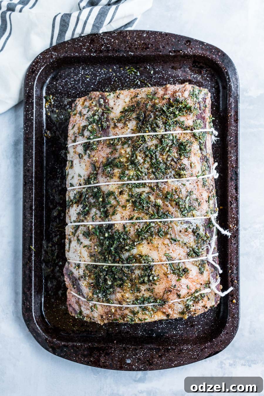 Juicy Prime Rib Masterpiece 4 An entire raw prime rib roast, neatly tied with kitchen twine, resting on a baking sheet.