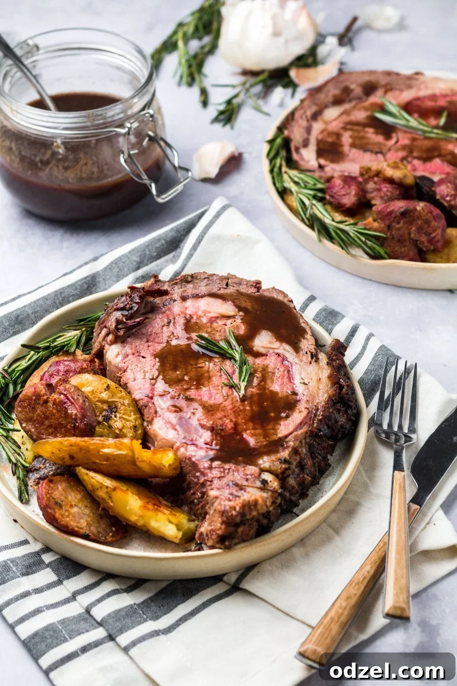 Juicy Prime Rib Masterpiece 6 A serving of medium-rare prime rib with au jus and creamy horseradish sauce, accompanied by roasted potatoes on a white plate.