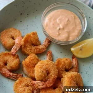 air fried shrimp on a blue plate with a lemon wedge and sauce in a bowl.