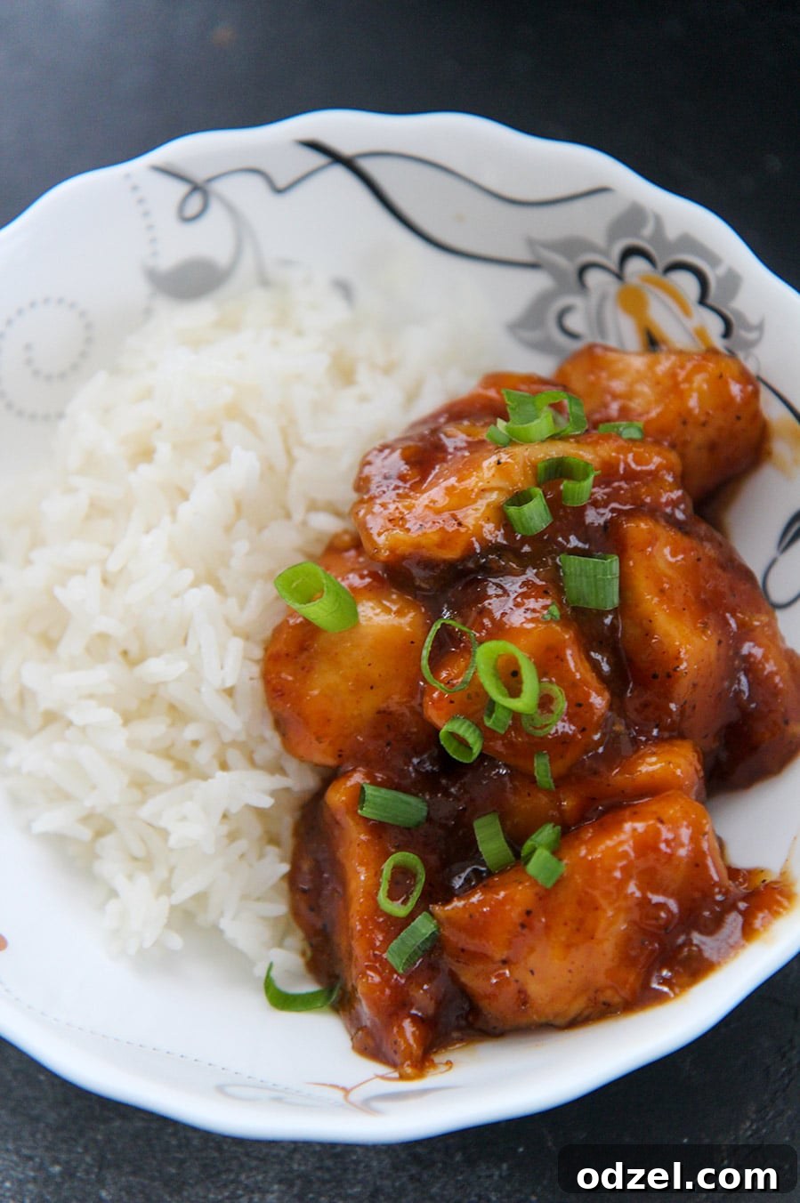 Tangy Orange Crock-Pot Chicken 3 Crockpot orange chicken garnished with fresh scallions, served alongside a mound of white rice for a complete meal.