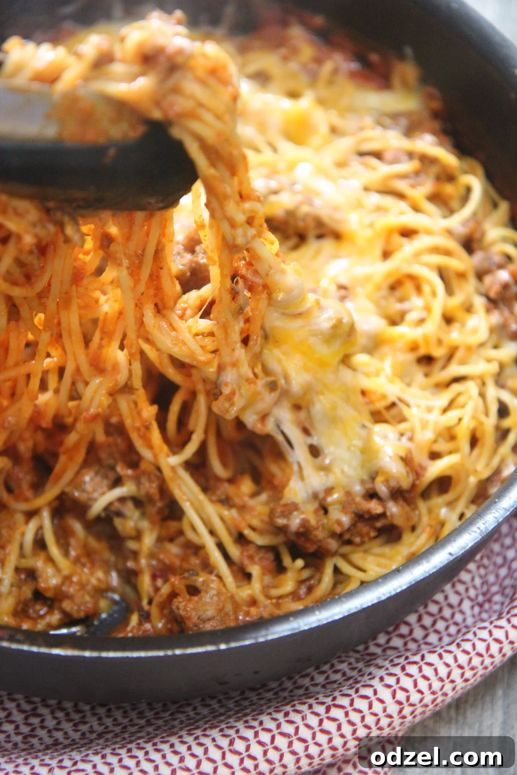 Perfectly seasoned, cheesy taco spaghetti is a quick dinner time solution. A close-up shot of taco spaghetti with melted cheese and herbs.