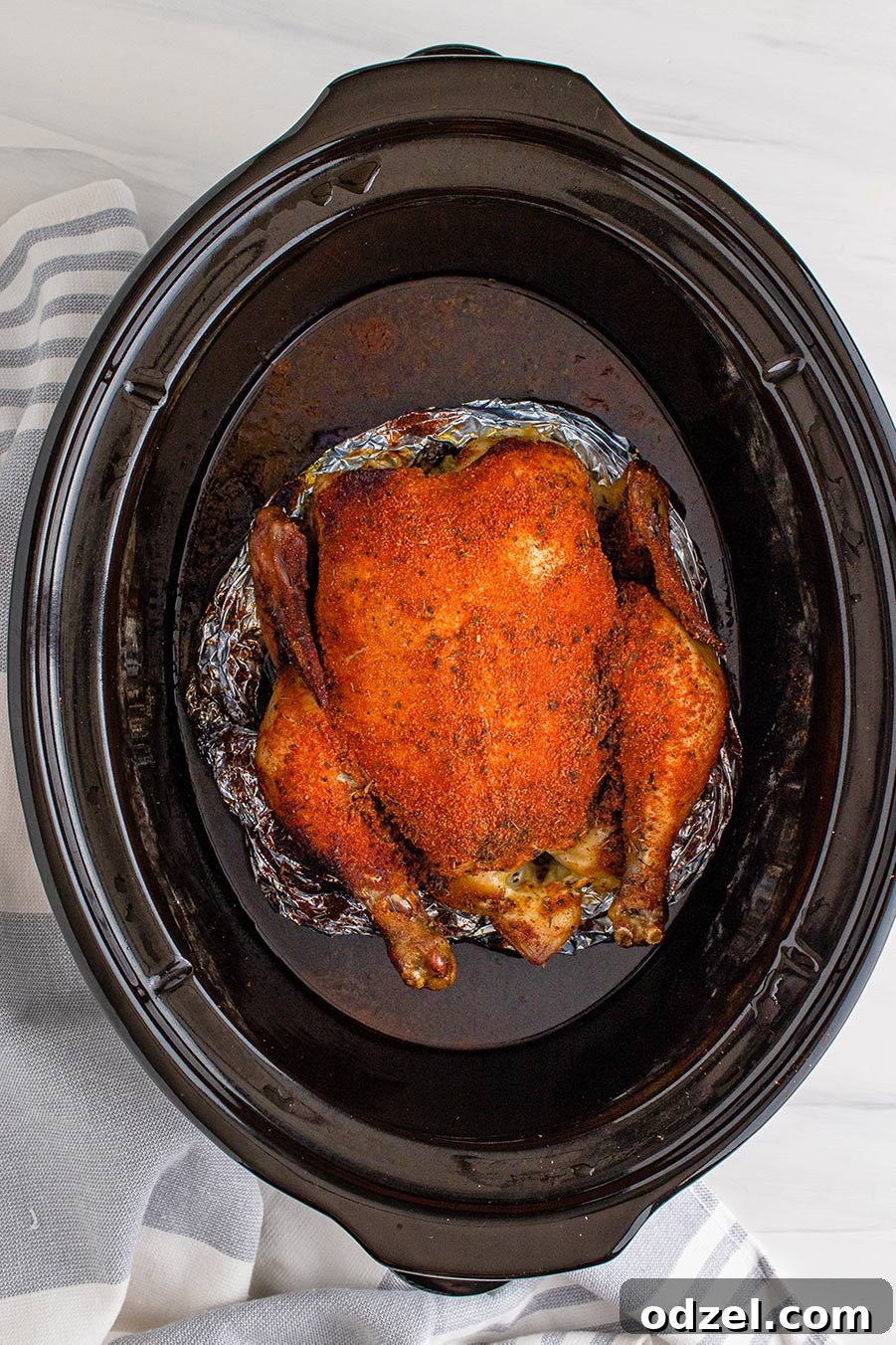 Fall-Off-The-Bone Slow Cooker Whole Chicken 3 slow cooker whole chicken on top of aluminum foil.