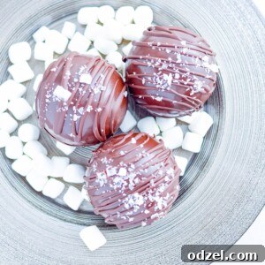 Three hot chocolate bombs on a plate with mini marshmallows.