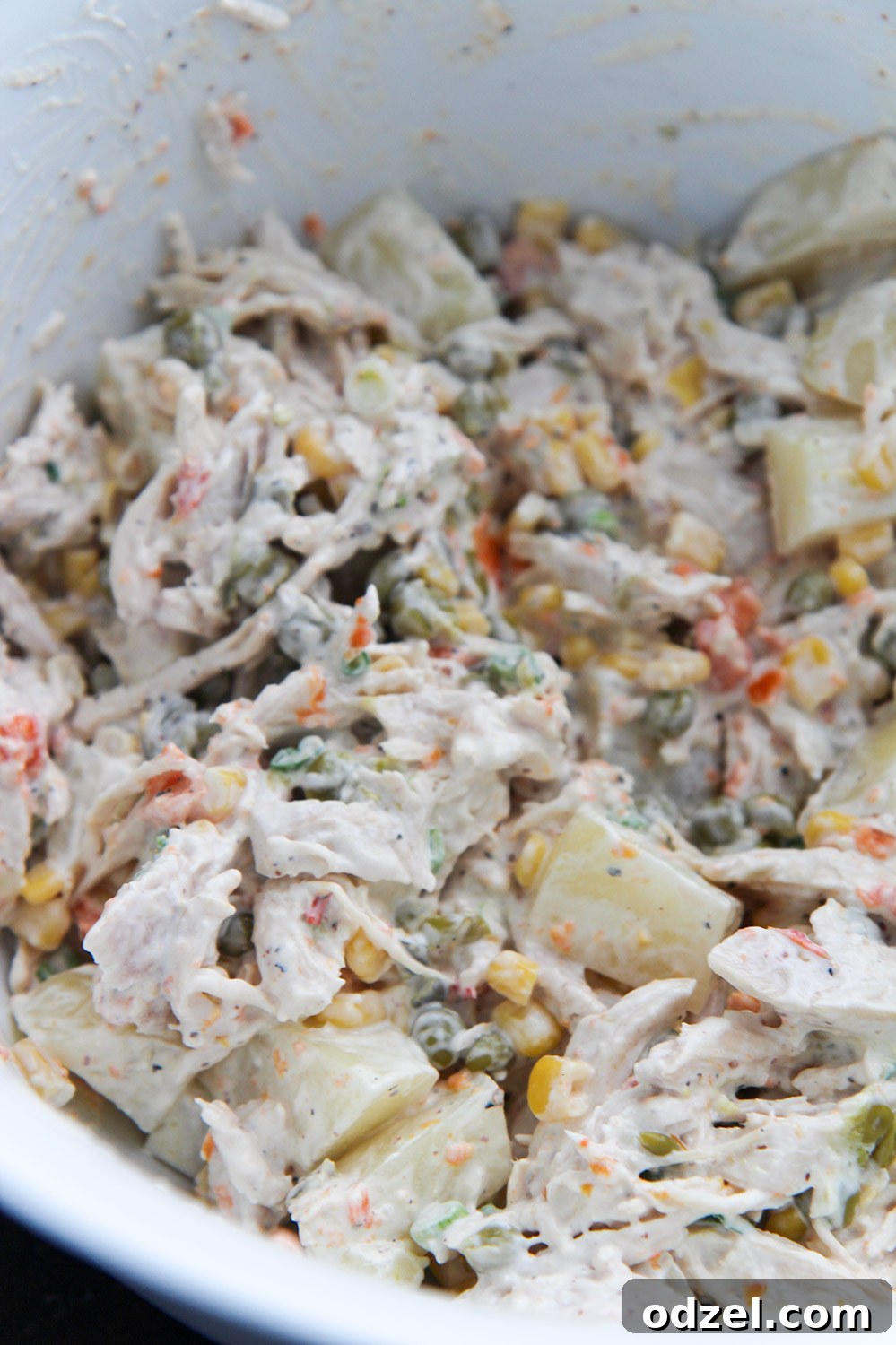 Creamy Mexican chicken salad in a white bowl, garnished with fresh cilantro and a lime wedge.
