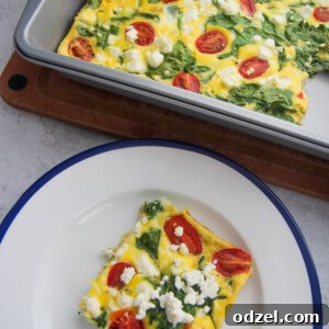 A delectable slice of spinach and goat cheese frittata, showcasing its fluffy texture and vibrant ingredients, resting on a white plate with a subtle blue pattern, ready to be enjoyed.