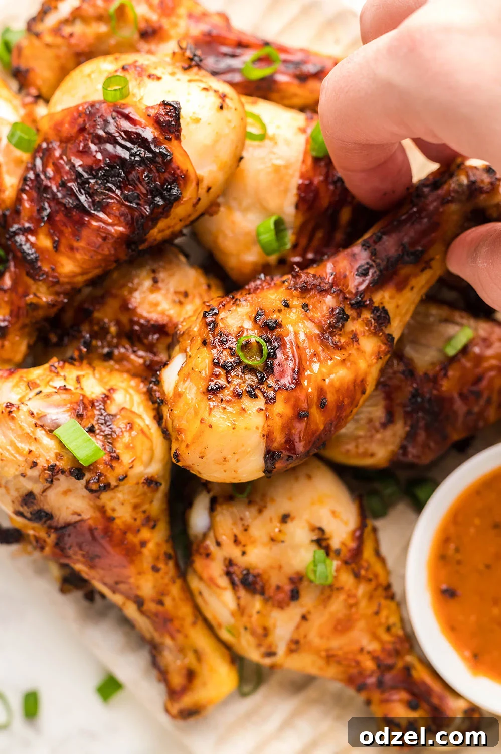 Juicy Crispy Air Fryer Drumsticks 2 Air fryer chicken drumsticks with a dip on the side and fresh scallions on top, showcasing a golden-brown, crispy finish.