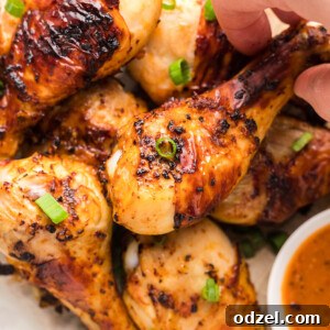 Air fryer chicken drumsticks with a dip on the side and scallions on top.