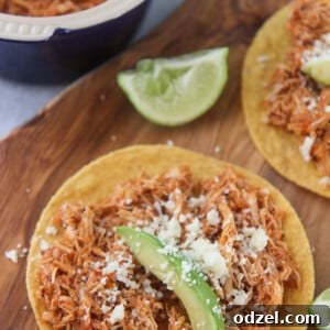 Smoky Instant Pot Chicken Tinga 6 chicken tinga tostadas on a wooden board with lime wedges on the side.