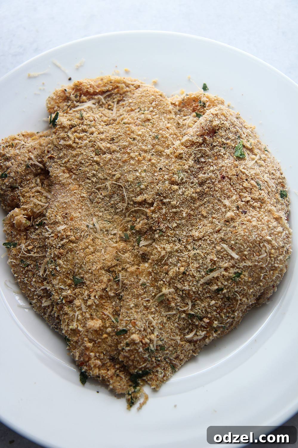 Golden Crunchy Chicken Cutlets 3 Two perfectly breaded chicken breasts resting on a white plate, showcasing their golden, crispy exterior, ready to be enjoyed.